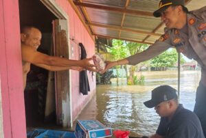 Kapolsek Muara Wahau, AKP Satria Yudha, memberikan bantuan makanan bagi korban banjir di Desa Nehas Liah Bing. (dok: ainun/katakaltim)